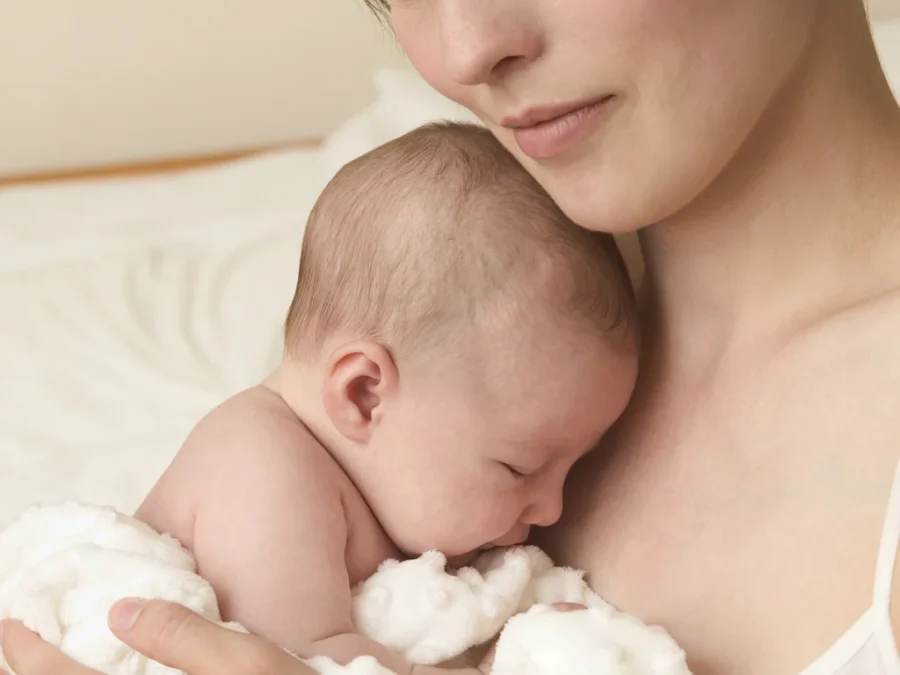 Mother holding her newborn baby — postpartum hair loss