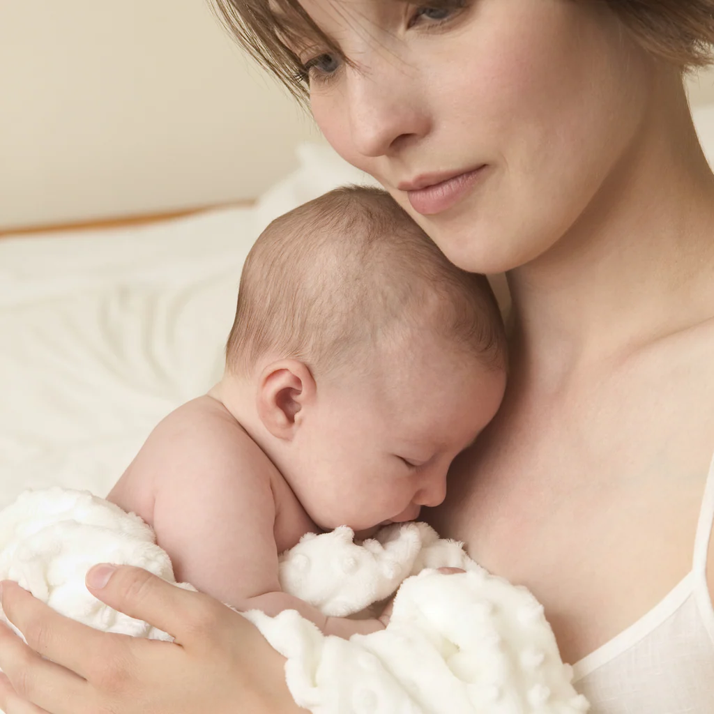 Mother holding her newborn baby — postpartum hair loss
