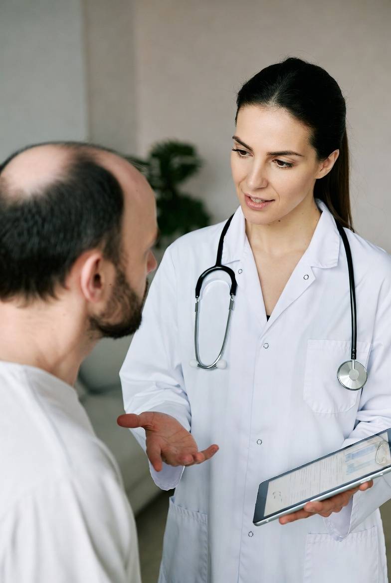 Trichologist examining a patient's scalp during a hair loss consultation