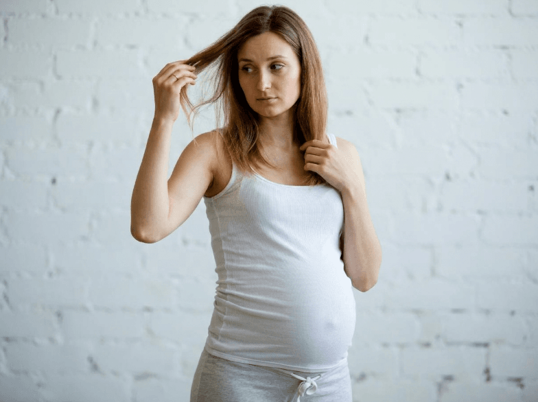 Pregnant woman examining her hair — hair changes during pregnancy