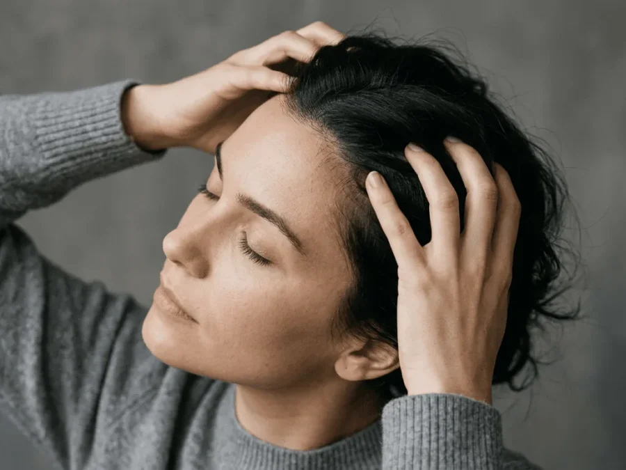 Woman massaging her scalp with both hands — scalp health